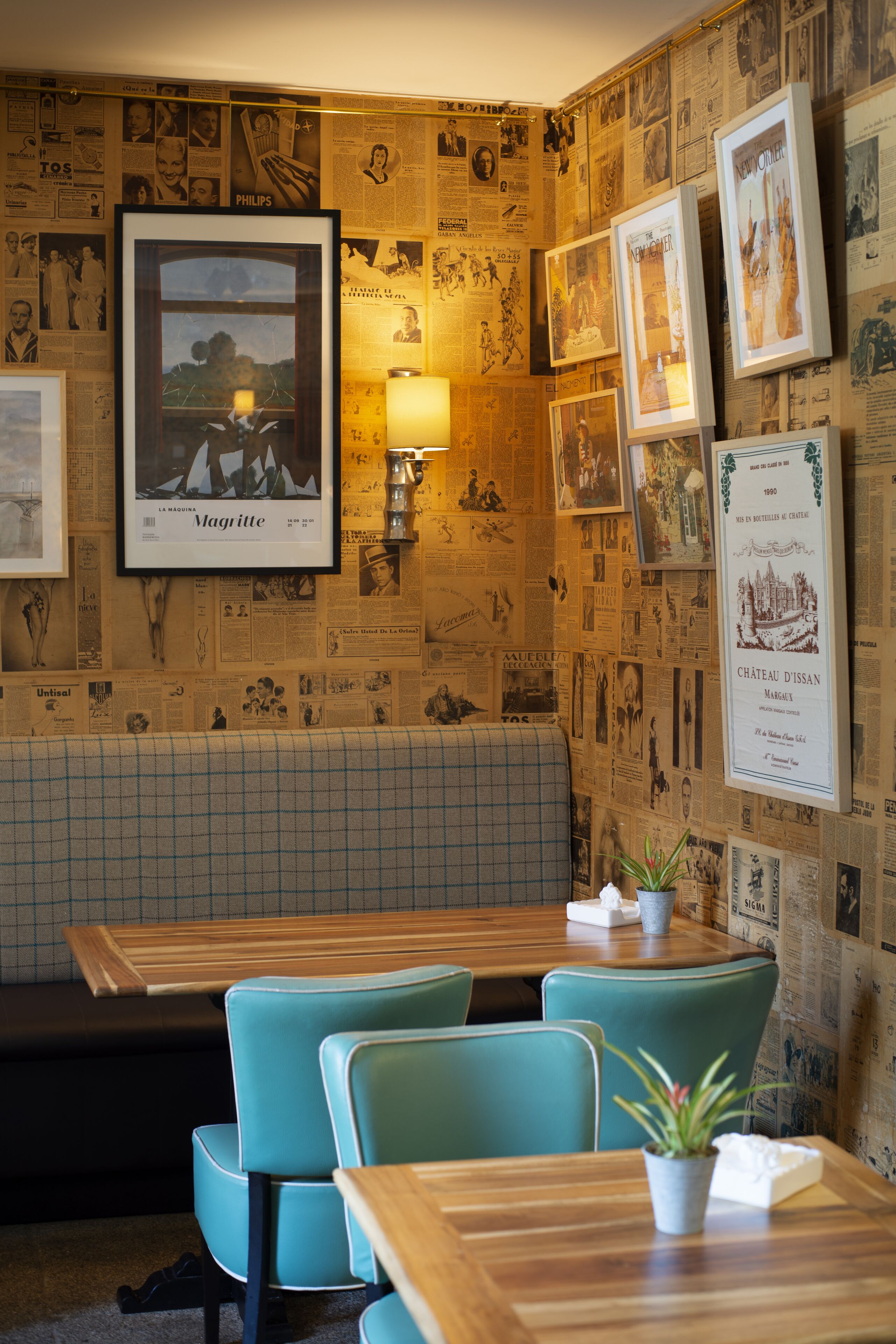 Ein Restaurant mit einer karierten Bank, smaragdgrünen Stühlen und gerahmten Bildern an der Wand.
