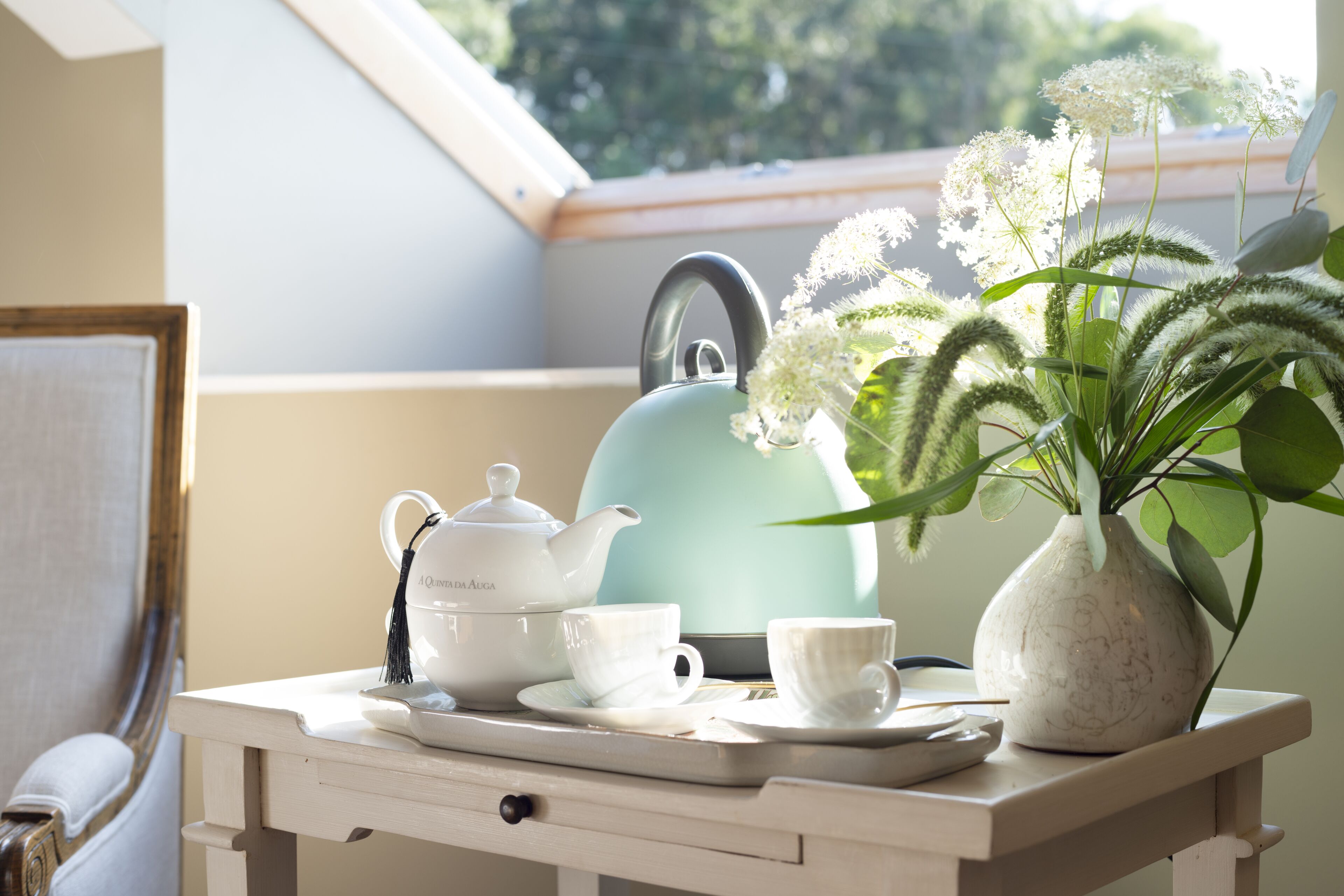Une table avec une théière, des tasses et un vase rempli de fleurs.