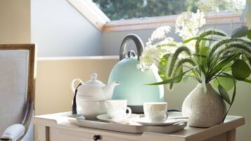 Une table avec une théière, des tasses et un vase rempli de fleurs.