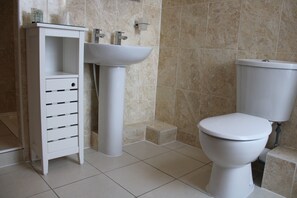 A bathroom with a white sink, a toilet, and a storage unit with drawers. - The Mardonia (Blackpool)