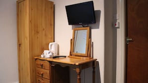 Une commode en bois avec des tiroirs, un miroir et un téléviseur fixé au-dessus.