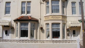 Un immeuble d’angle avec une enseigne indiquant « Hôtel Mardonia » et « Toutes les chambres sont équipées d’une salle de bain privée ».