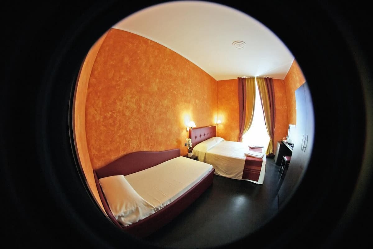 A hotel room with two beds, a desk, and a TV.