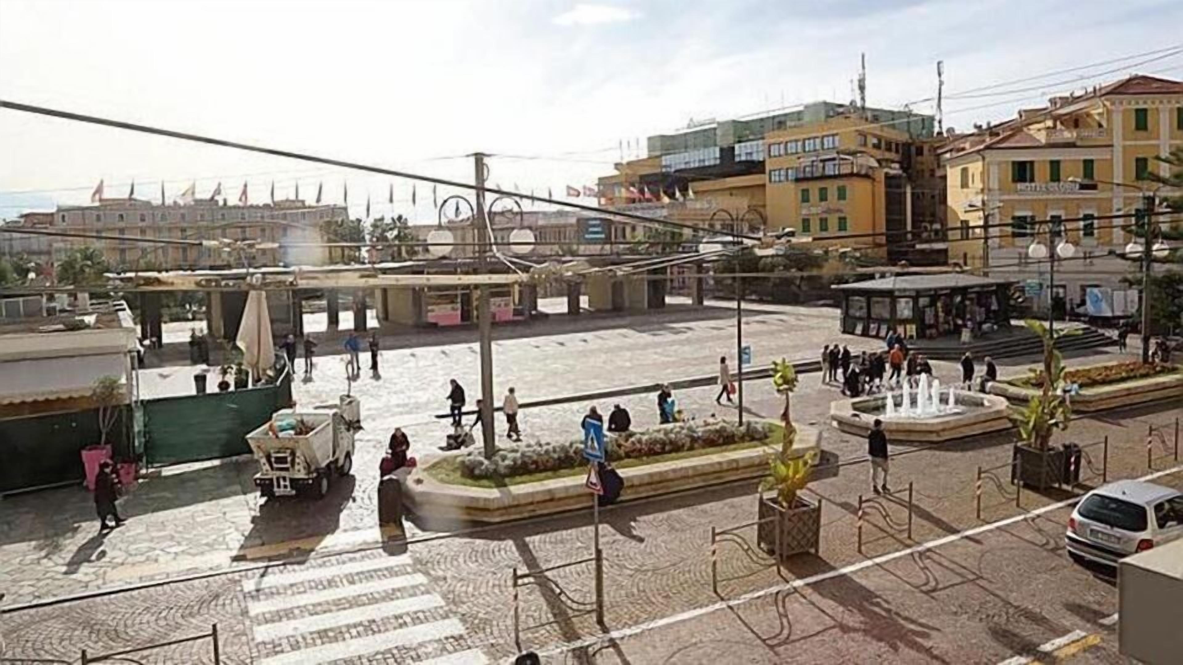 Une place publique avec une fontaine, des espaces aménagés pour s’asseoir et un passage piéton.