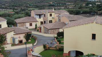 Una zona residencial con tejados de tejas color terracota, una calle pavimentada y una persona montando en bicicleta.