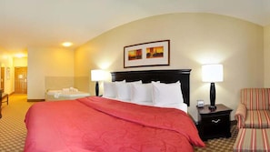 A hotel room with a large bed, two bedside lamps, a chair, a small table with a lamp, and a picture on the wall. - Country Inn & Suites by Radisson, Conway, AR (Conway)