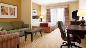 A hotel room with a bed, a sofa, a desk, and a television. - Country Inn & Suites by Radisson, Conway, AR (Conway)