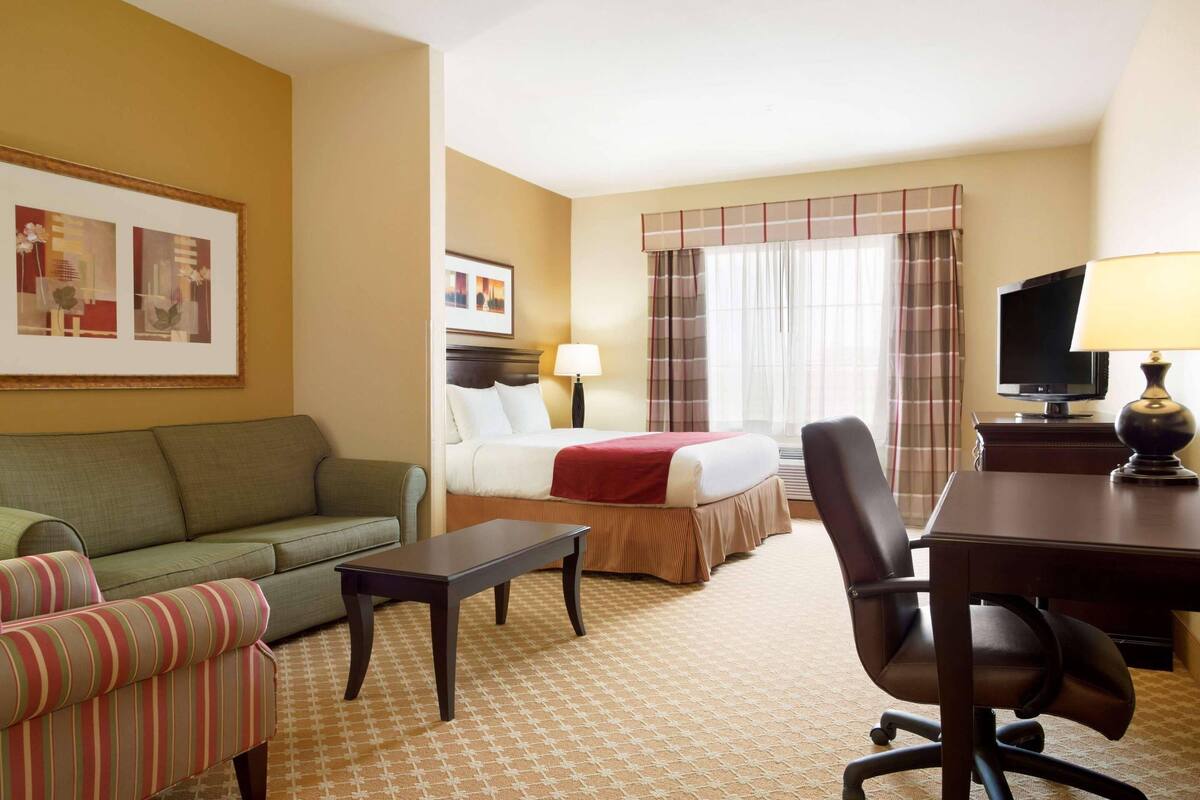 Une chambre d’hôtel avec un lit, un canapé, un bureau et une télévision.