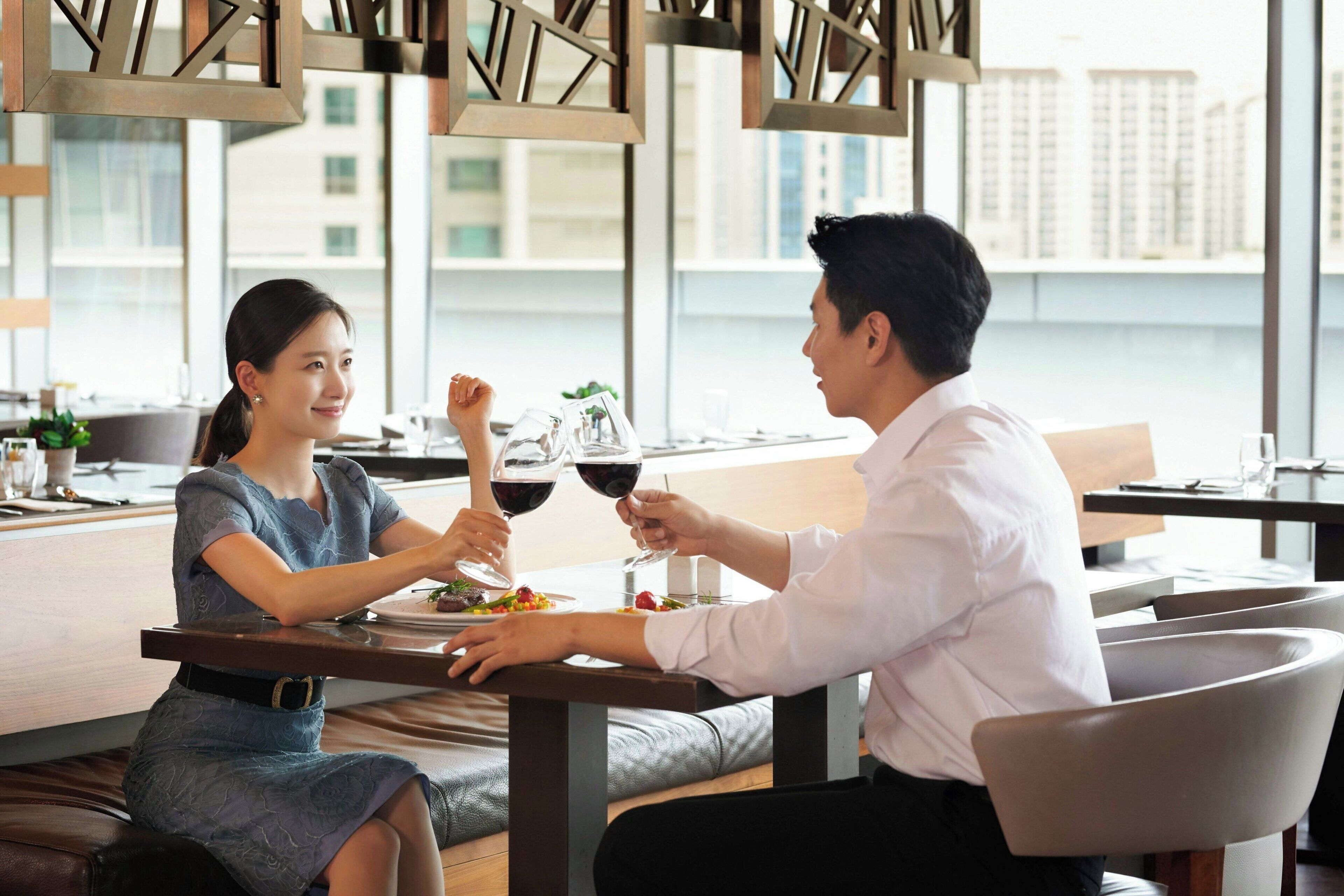 A couple dining at a table with a view of a cityscape.