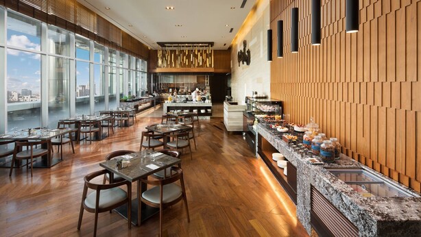 A modern restaurant with wooden flooring, large windows, and a buffet area.