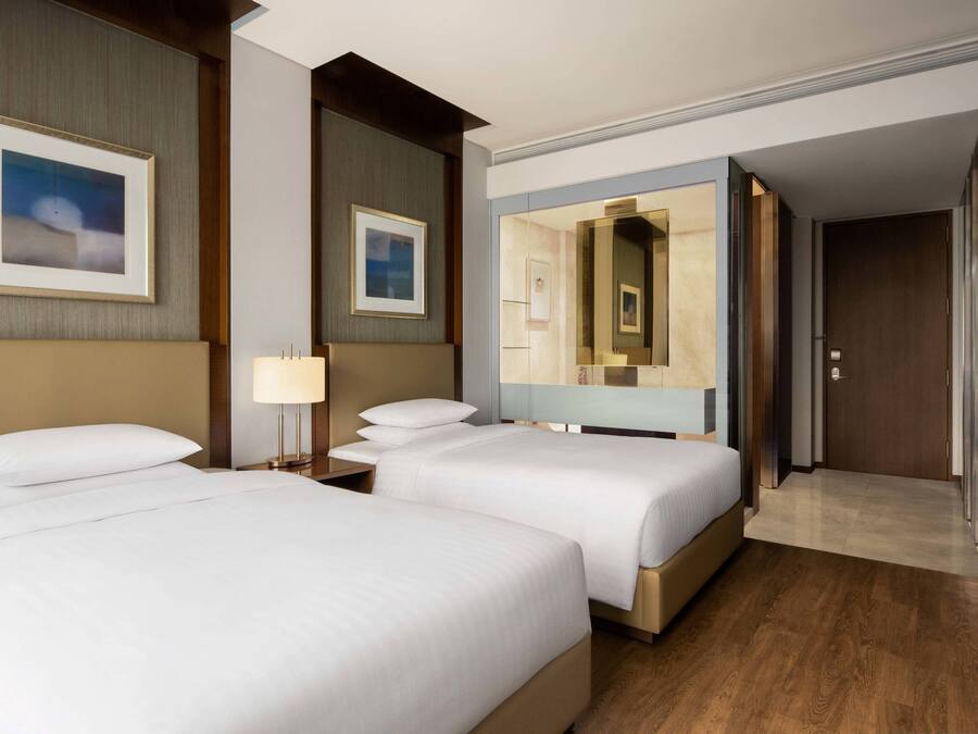 Une chambre d’hôtel avec deux lits, un grand miroir et un plancher en bois.