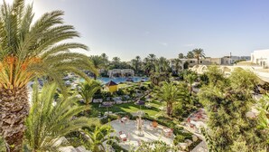 Un resort con piscina, palmeras y zonas de estar al aire libre.