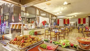 Un área de bufé con diversas opciones de comida y un comedor con mesas y sillas.