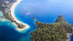 An aerial view of a coastal area with a beach, boats, and a parasail. - TUI MAGIC LIFE Sarigerme - All Inclusive (Ortaca)