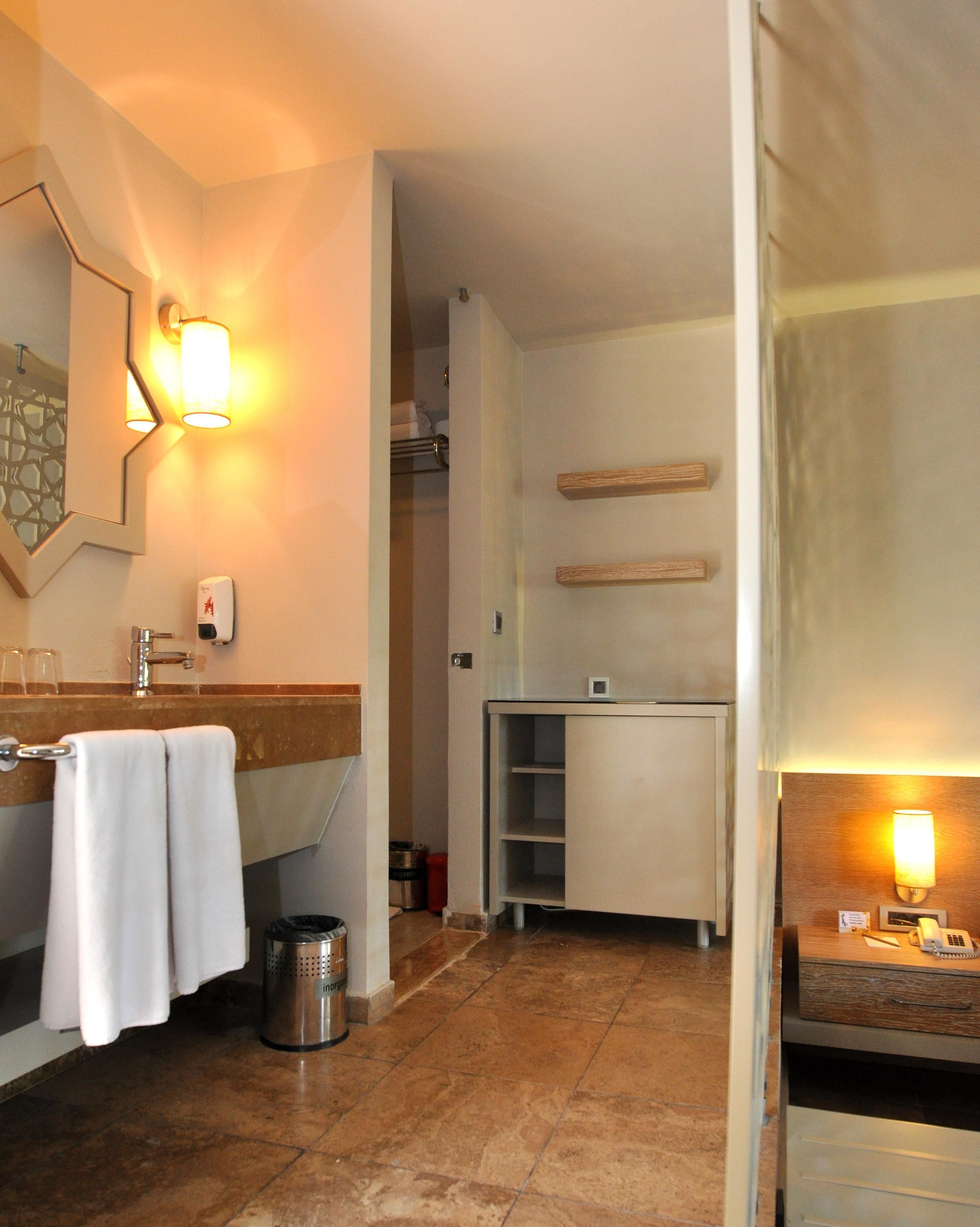 A hotel bathroom with a sink, mirror, towel rack, and a trash can.