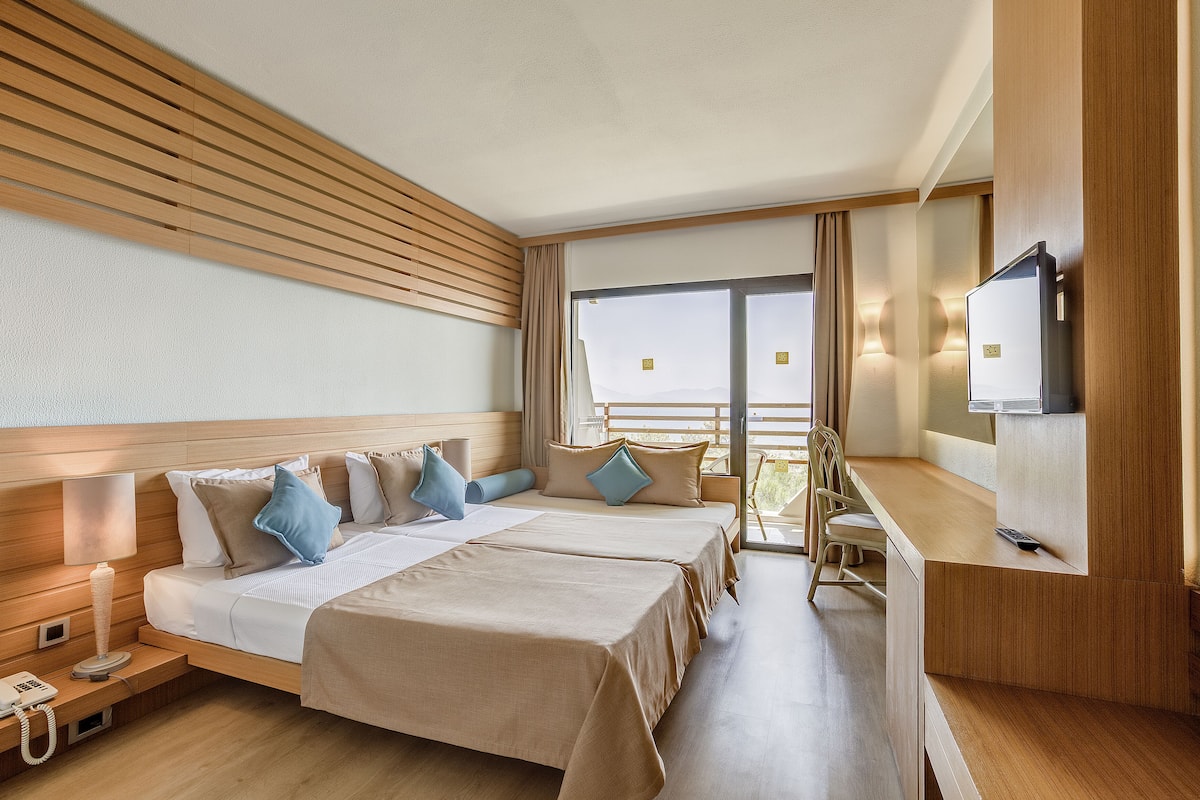 Ein Hotelzimmer mit zwei Betten, einem Schreibtisch, einem Fernseher und einem Telefon auf dem Nachttisch.