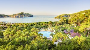 A resort with a central pool surrounded by lush greenery, a view of the sea, and a hilly landscape. - TUI MAGIC LIFE Sarigerme - All Inclusive (Ortaca)