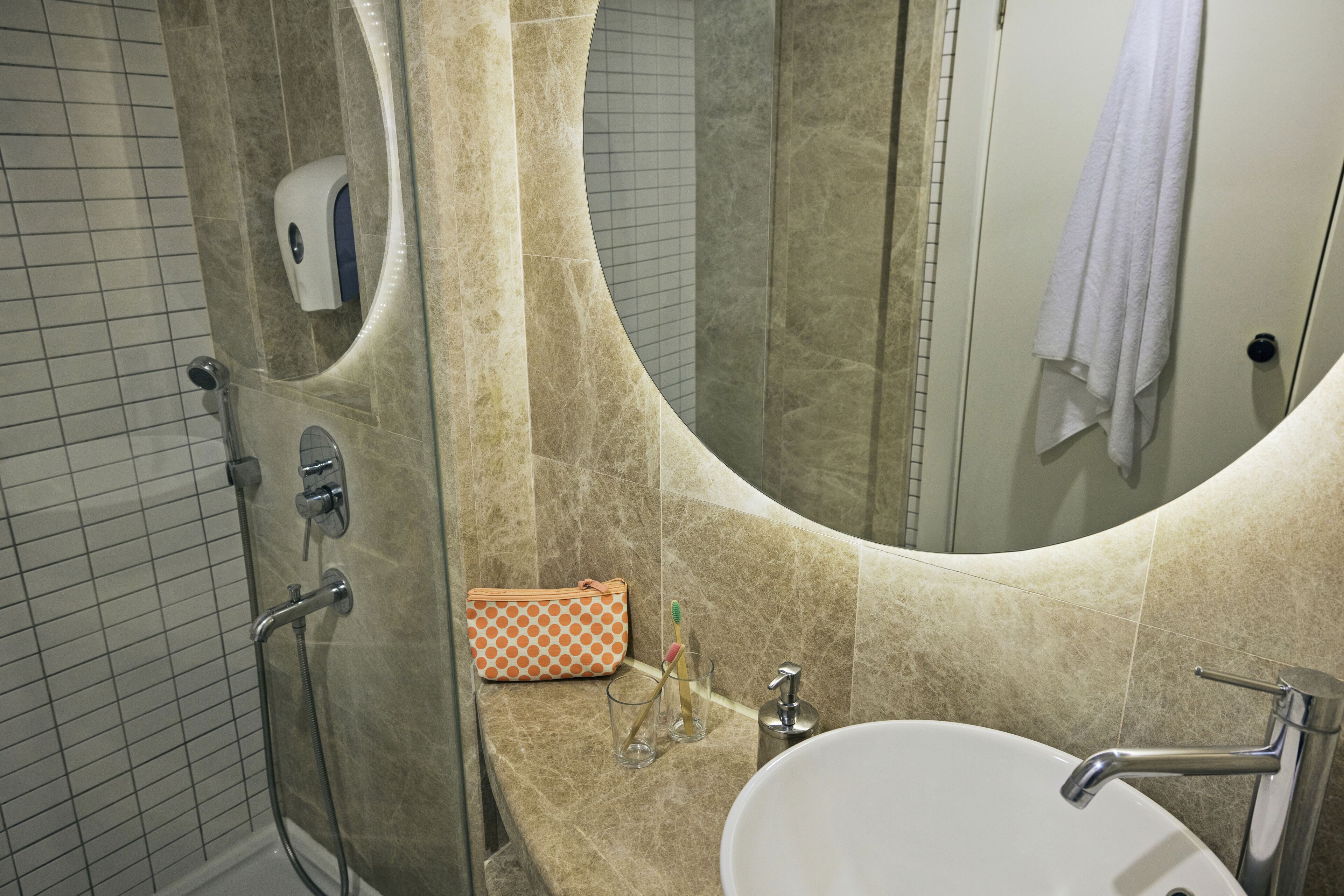 A bathroom with a large mirror, a sink, and a shower.
