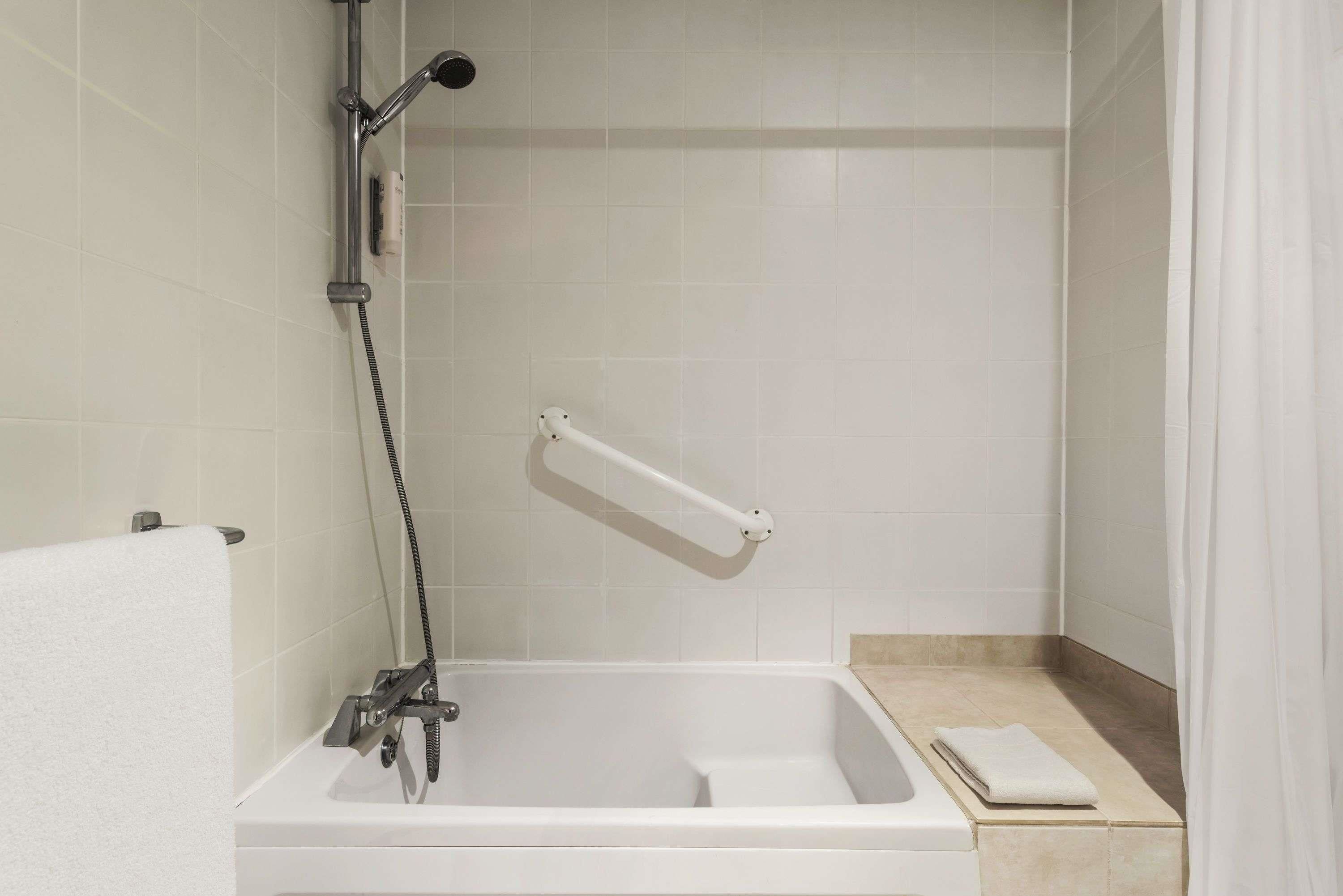 A bathroom with a bathtub, a showerhead, and a towel rack.