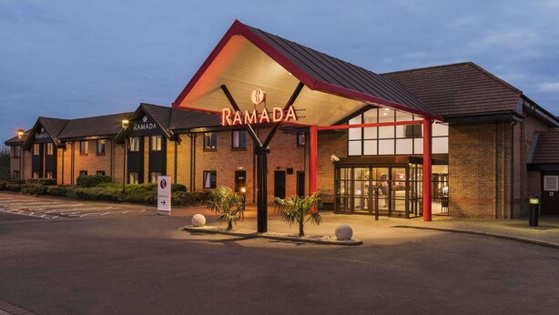 Um hotel chamado Ramada, com design moderno, apresentando uma entrada destacada e uma área coberta.