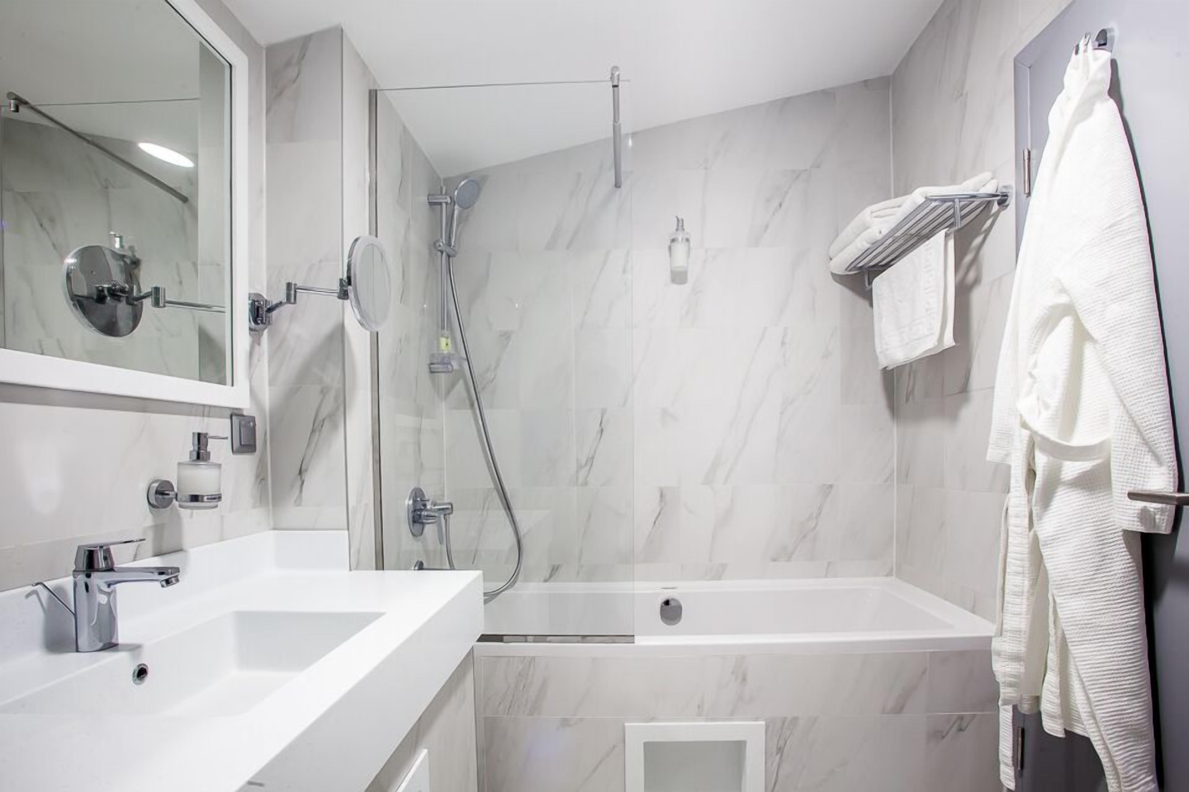 Een moderne badkamer met een douchecabine van glas, een vrijstaand bad en een grote spiegel boven de wastafel.