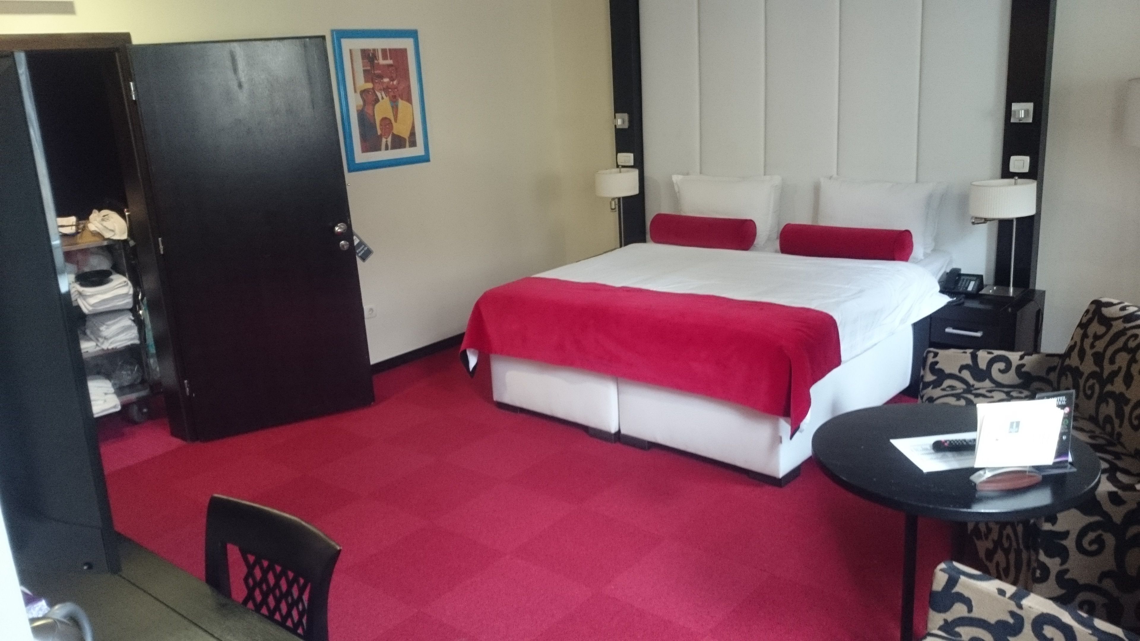 A hotel room with a bed, a desk, a chair, and a wardrobe.