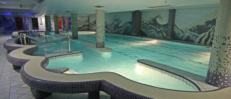 An indoor swimming pool with tiled walls and benches.