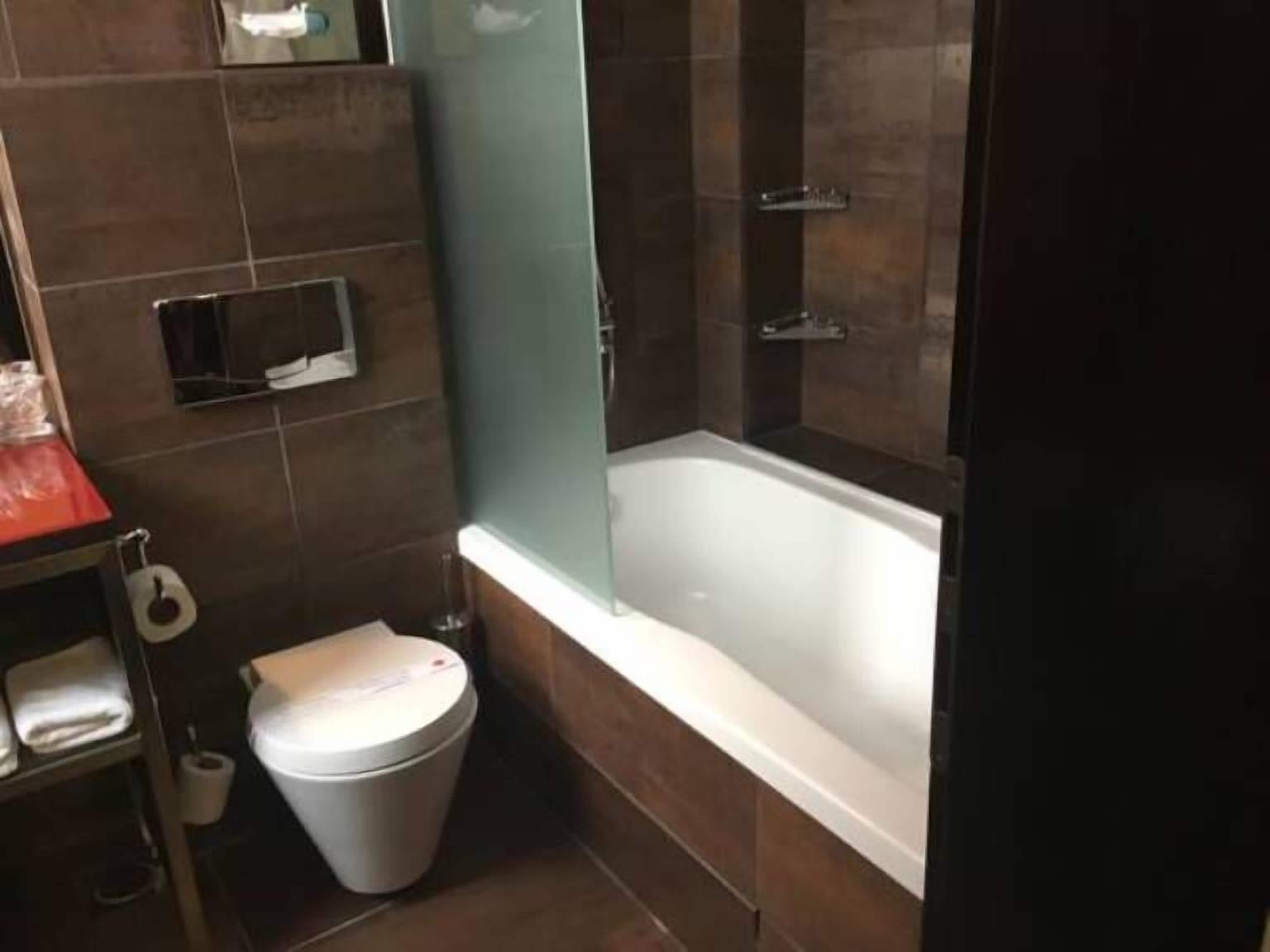 Un baño con bañera, inodoro y un perchero para toallas.