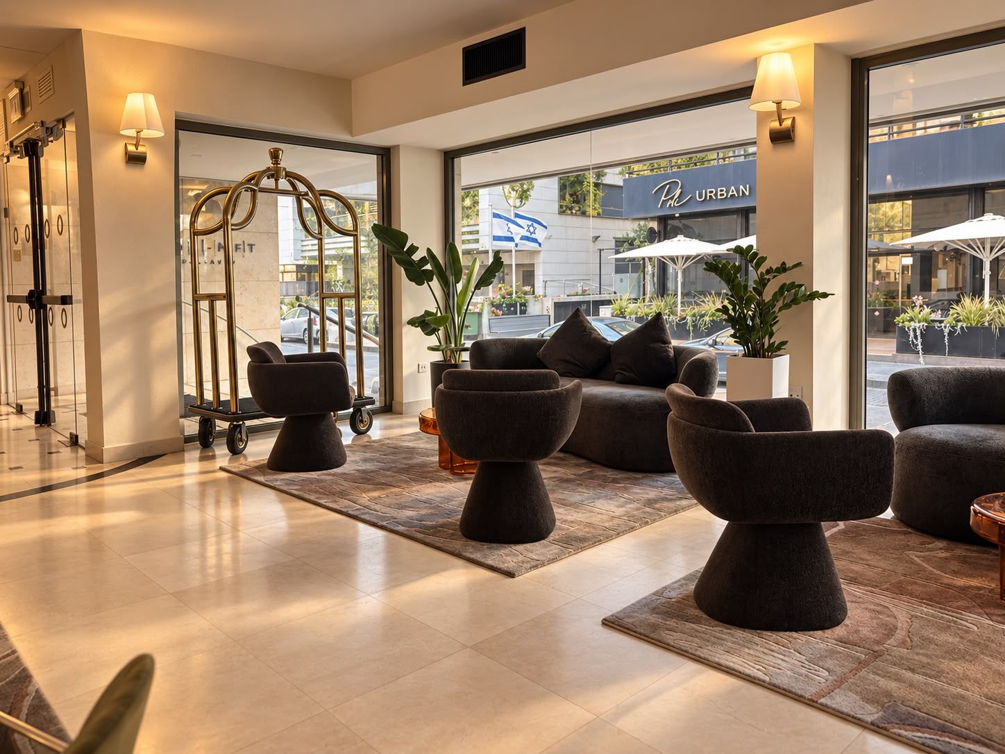 A modern lobby with a reception desk, seating area, and large windows offering a view of the street.