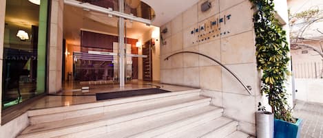 A hotel entrance with a glass door, a staircase, and a wall with a sign.