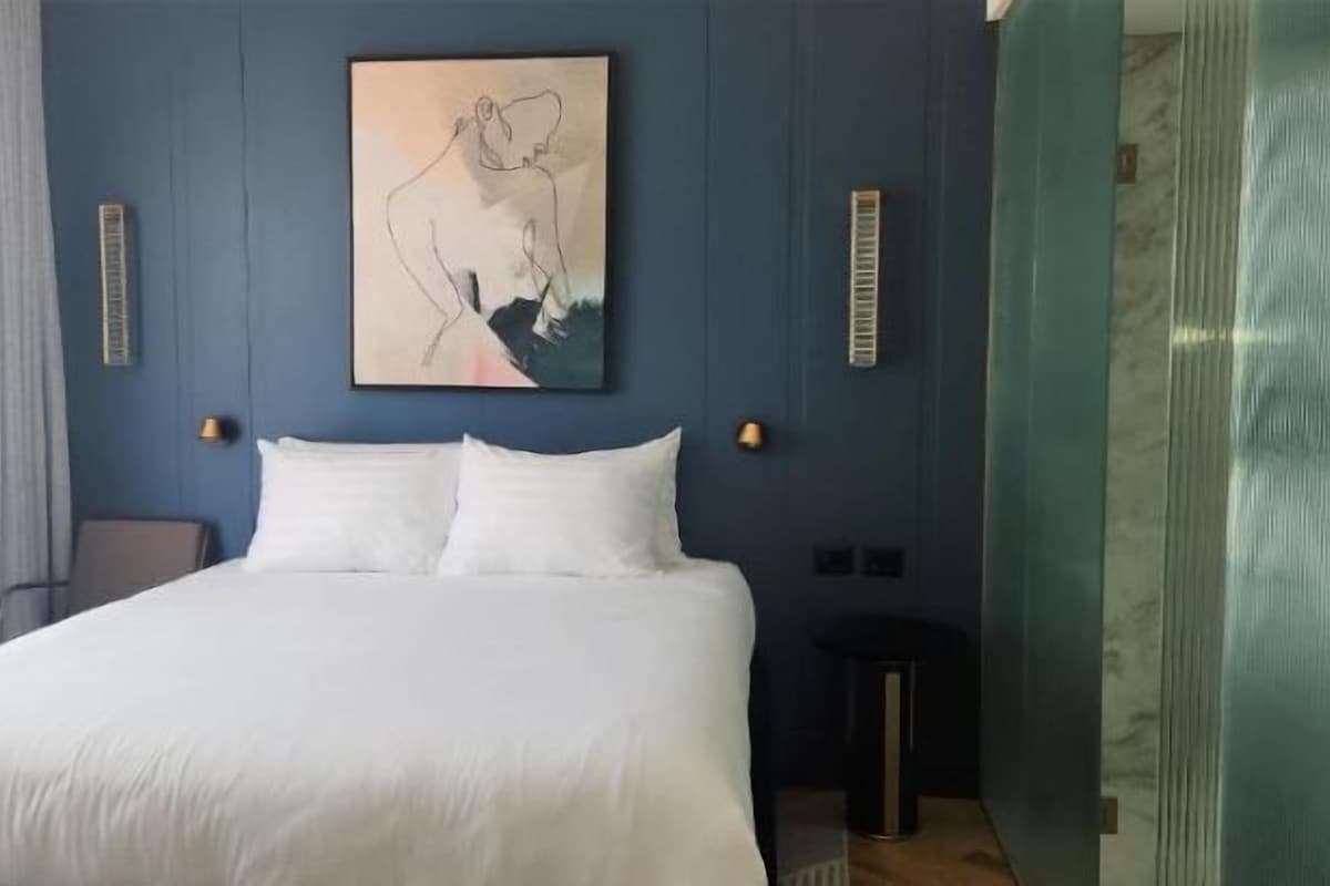 Un dormitorio con una cama grande, un cuadro en la pared y una ventana con cortinas.