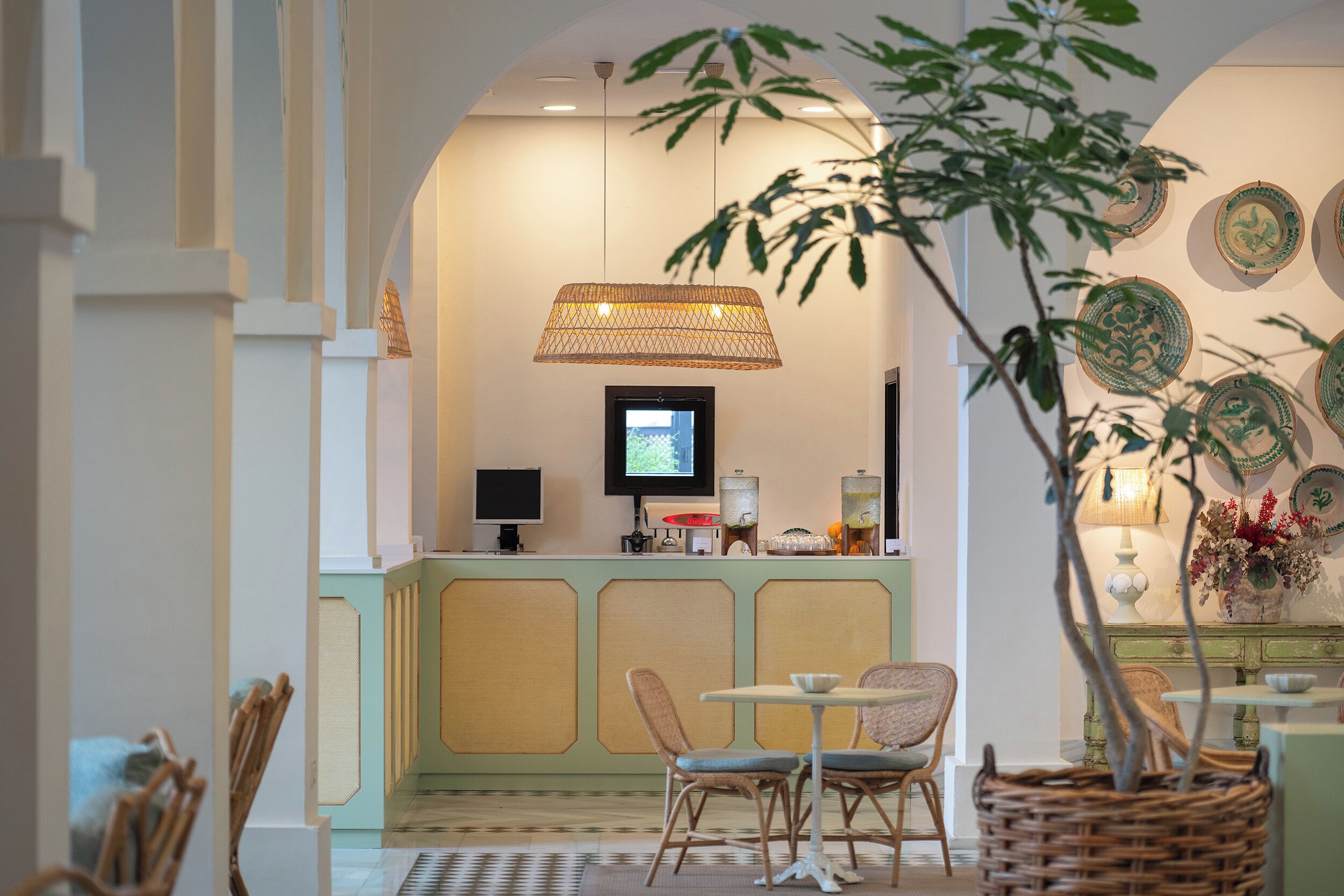 Zona de recepción con televisor, mostrador y área de descanso con sillas y una mesa.