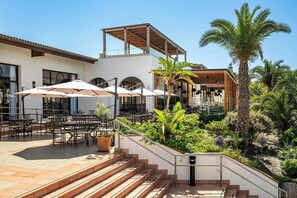 A patio area with outdoor seating, a staircase, and a palm tree. - Impressive Playa Granada Golf (Motril)