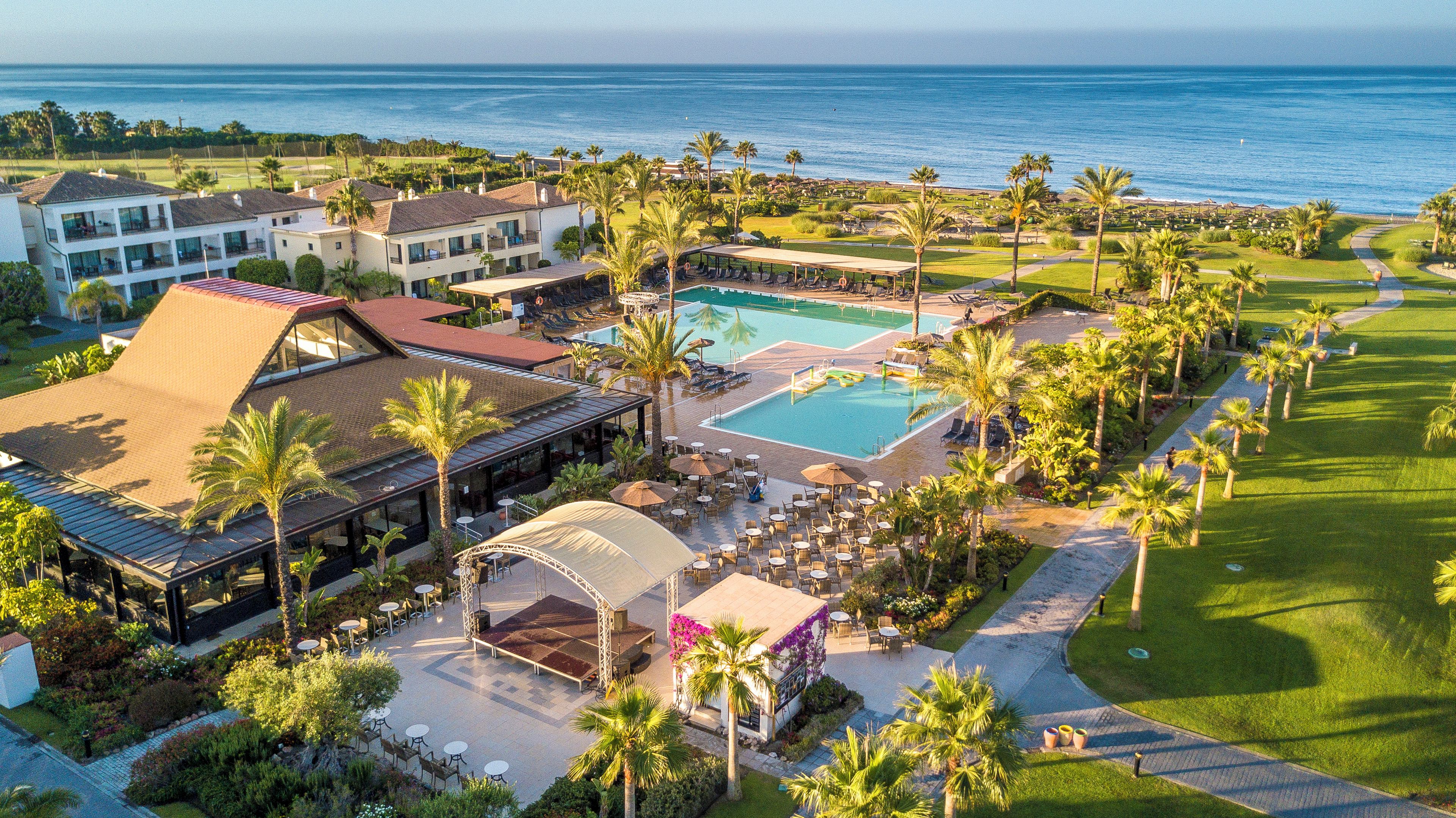 Un resort con piscina, mobiliario exterior y vista al océano.