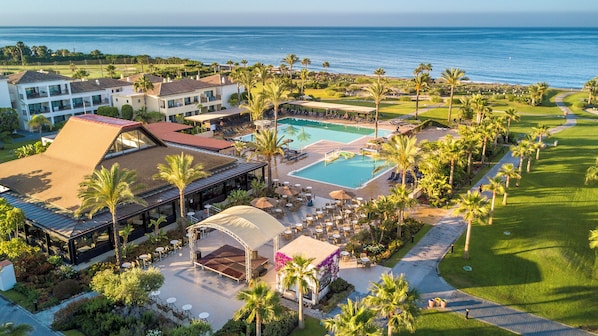 Un resort con piscina, mobiliario exterior y vista al océano.