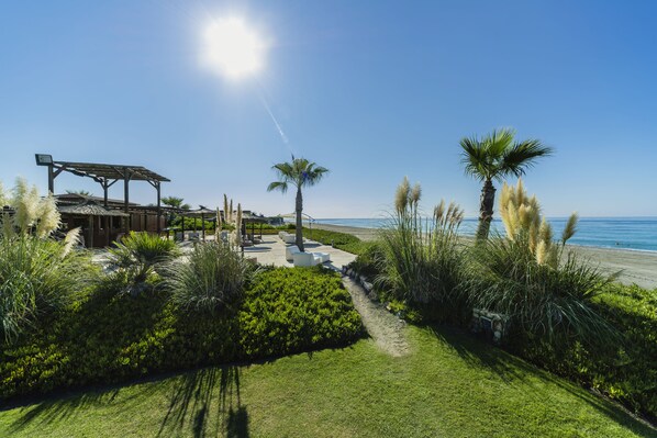 A pathway leading to a beach area with palm trees and a pergola structure. - Impressive Playa Granada Golf (Motril)