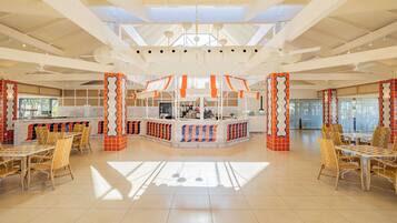 Amplio espacio interior con una barra central, diferentes disposiciones de asientos y un techo alto con vigas y luminarias a la vista.