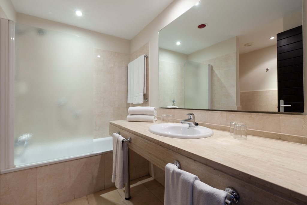 Un baño moderno con una bañera, un lavabo y un espejo grande.