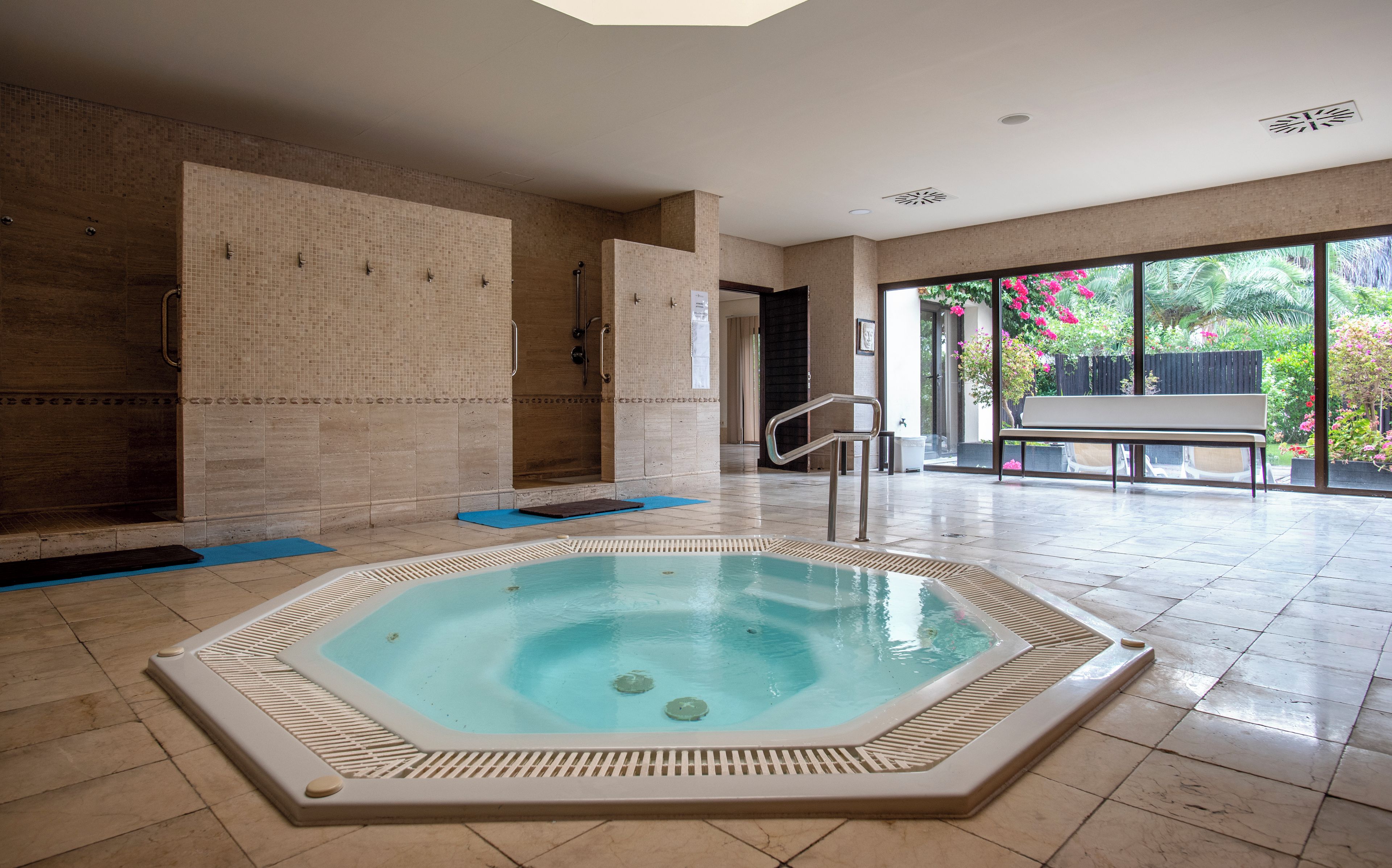 Un área de spa con un jacuzzi, una ducha y un banco.