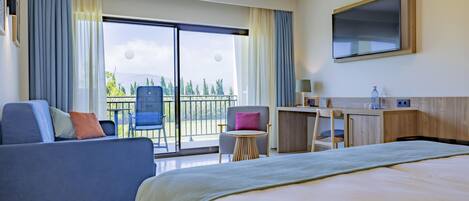 A hotel room with a bed, a sofa, a desk, a chair, and a balcony with a view.
