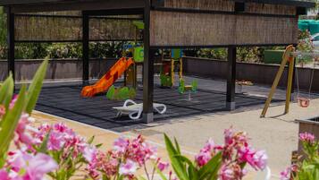 Children can play on the slide and play structures under the covered deck.