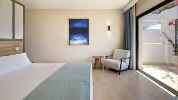 Habitación de hotel con cama, una silla, una mesita y un cuadro en la pared.