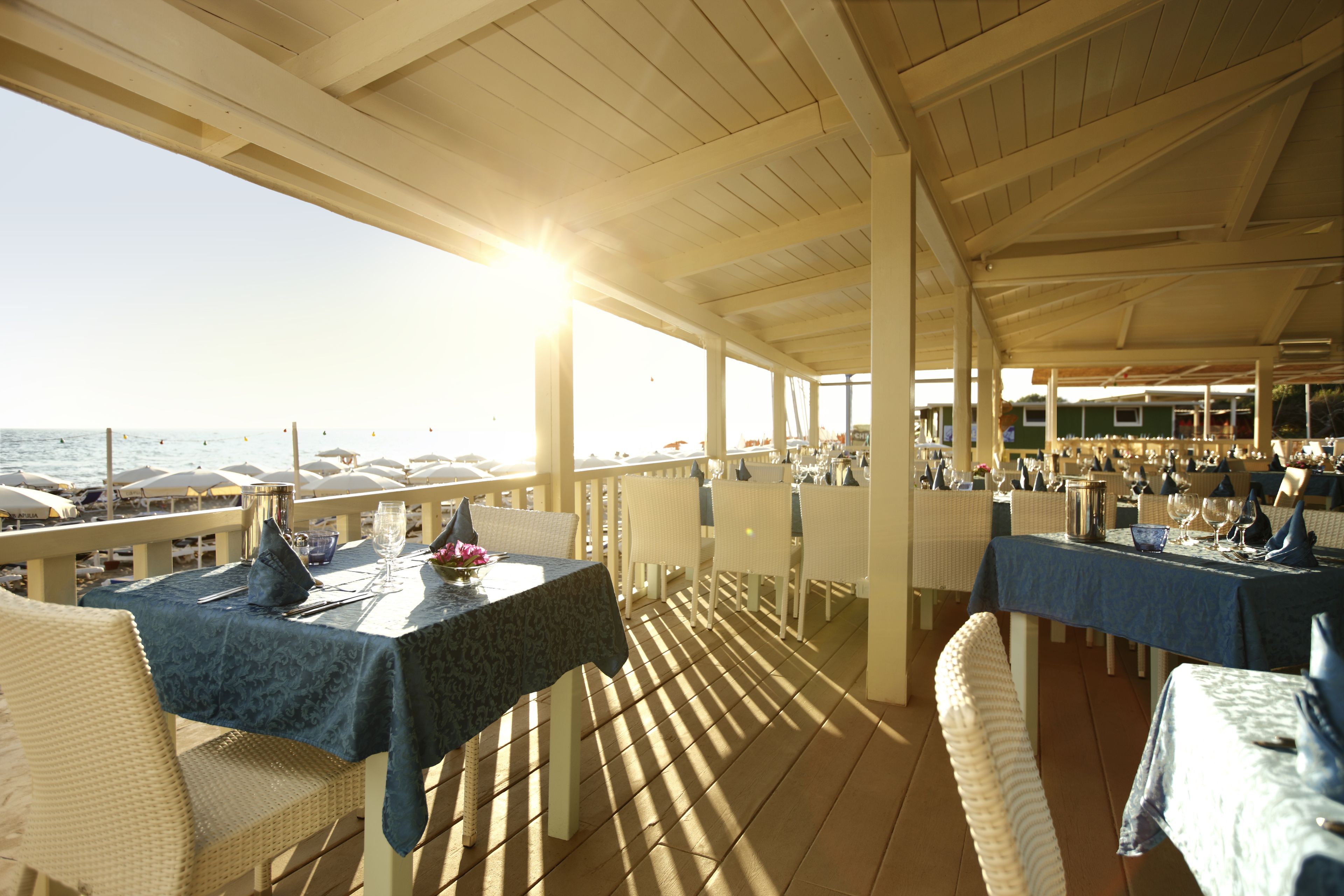 An outdoor dining area with tables and chairs, overlooking the sea.