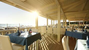 An outdoor dining area with tables and chairs, overlooking the sea.