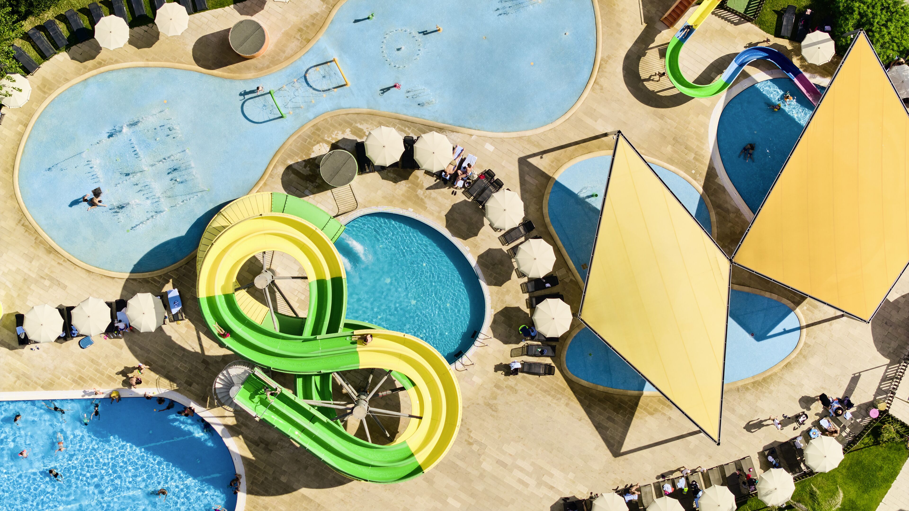 Ein Wasserpark mit mehreren Pools, Rutschen und Sonnenschirmen.