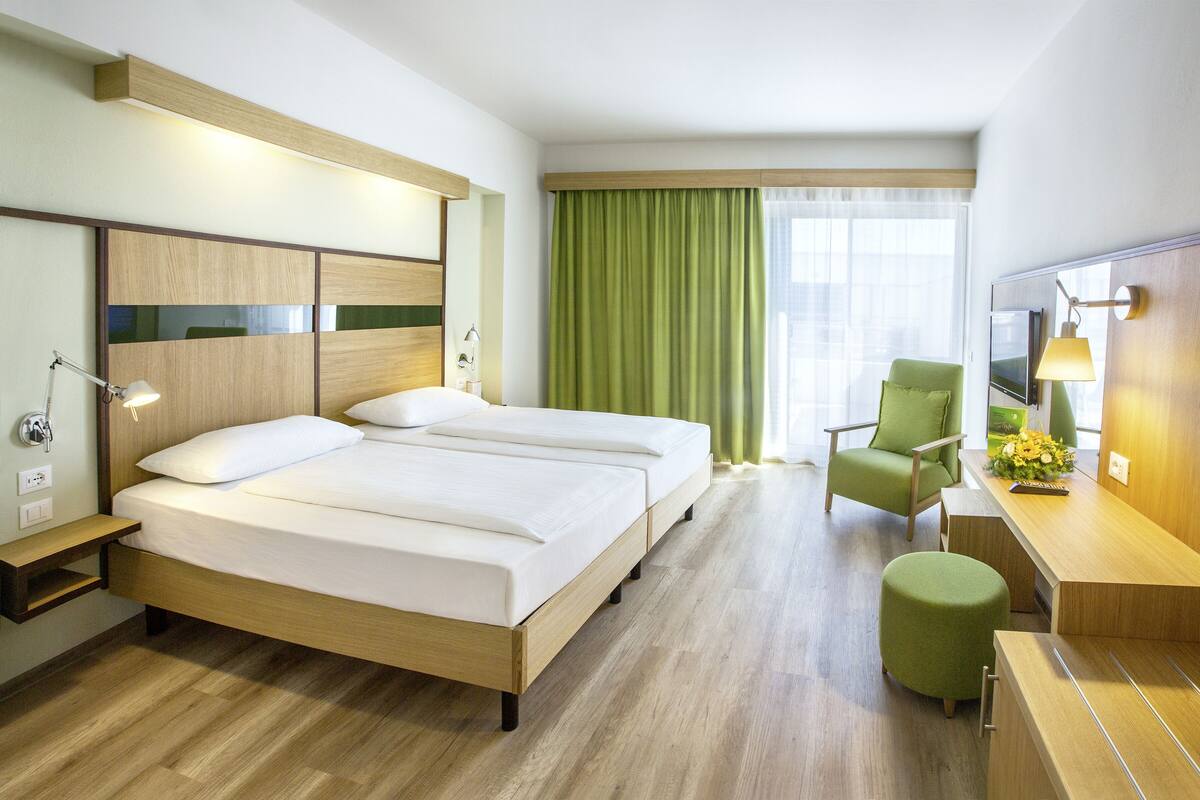A hotel room with a bed, a desk, a chair, and a TV.