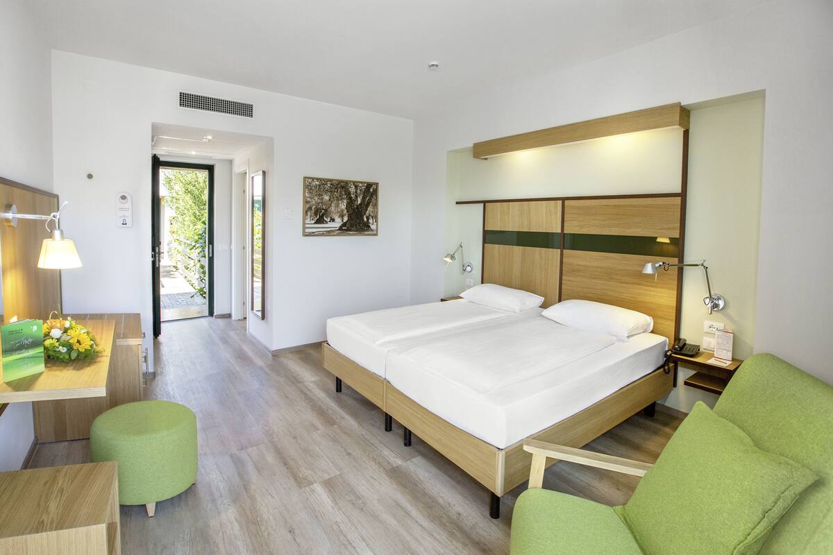 A hotel room with a bed, a desk, a chair, and a view of the outdoors.