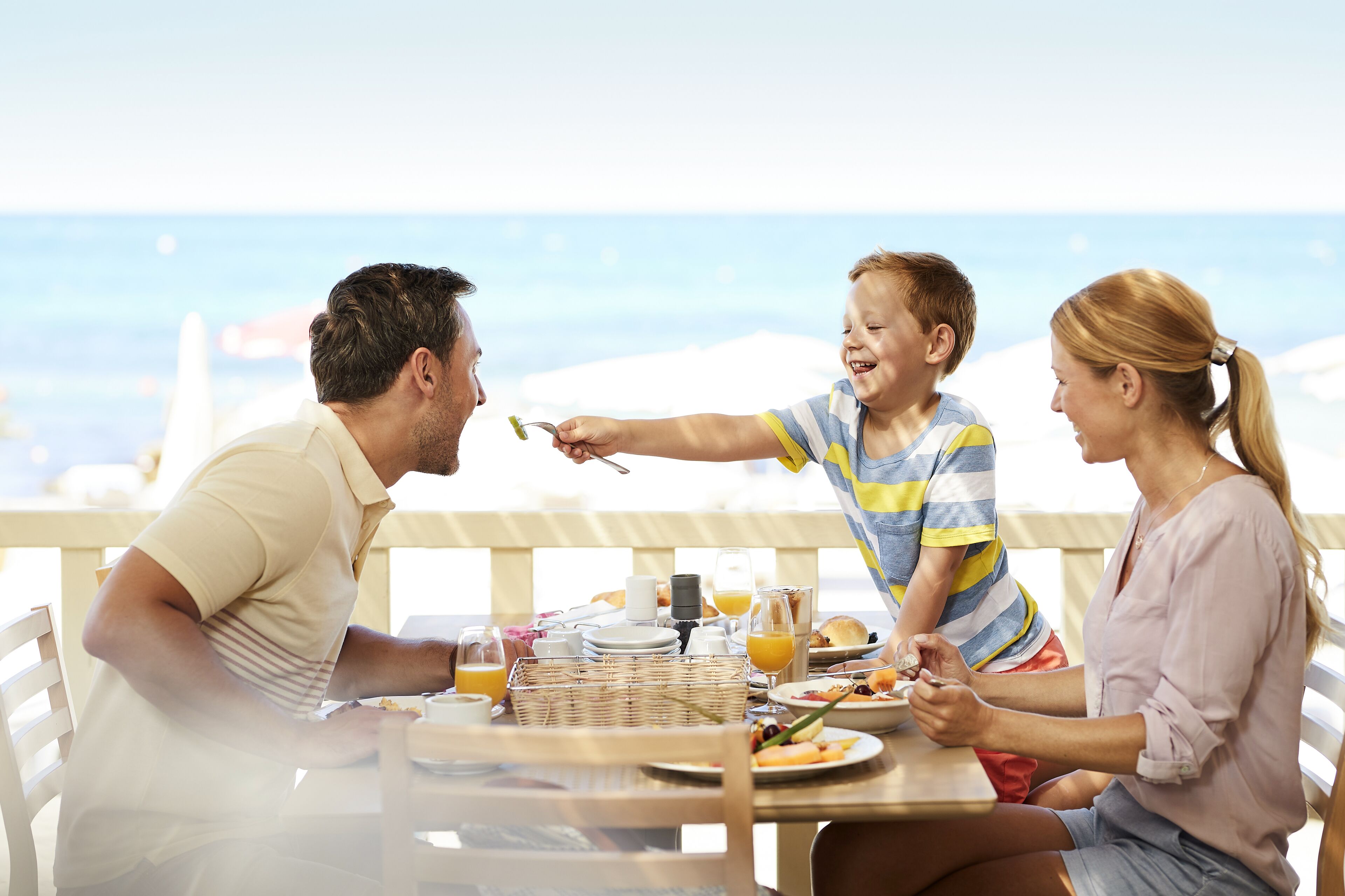 Una familia cenando en una mesa con vista al océano.
