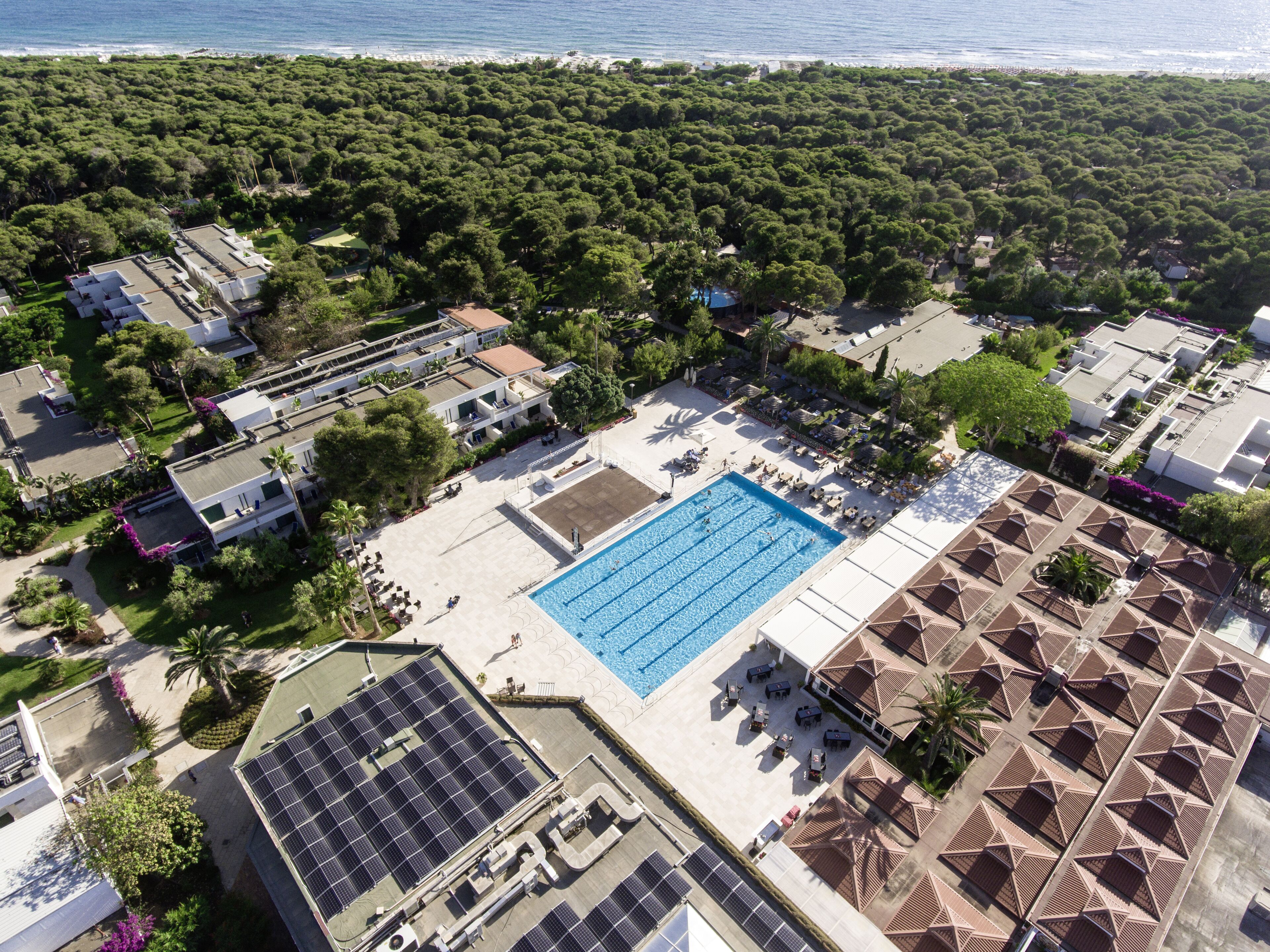 Eine Luftaufnahme eines Resorts mit Schwimmbad, Solaranlagen und Zugang zum Strand.
