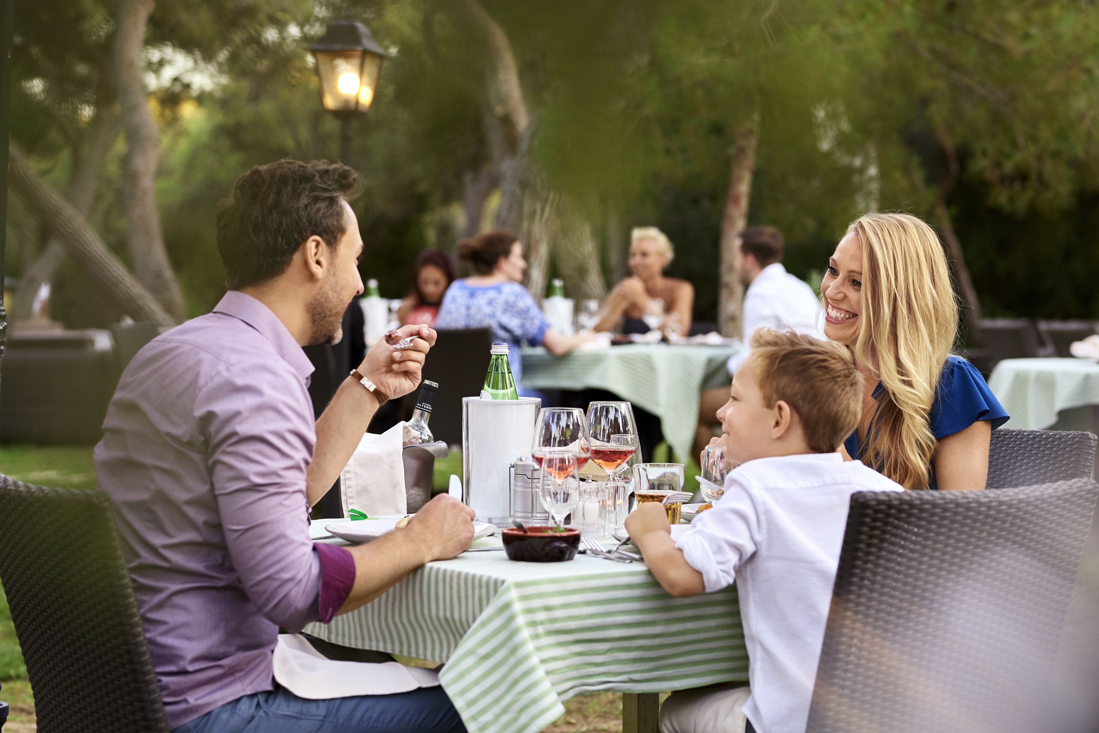 A family dining outdoors with a table set for a meal.